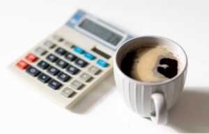 calculator with white ceramic cup containing black coffee.